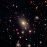 a picture of a galaxy cluster observed by the WISE and Spitzer Space Telescopes. The bright galaxy at the center is the BCG.